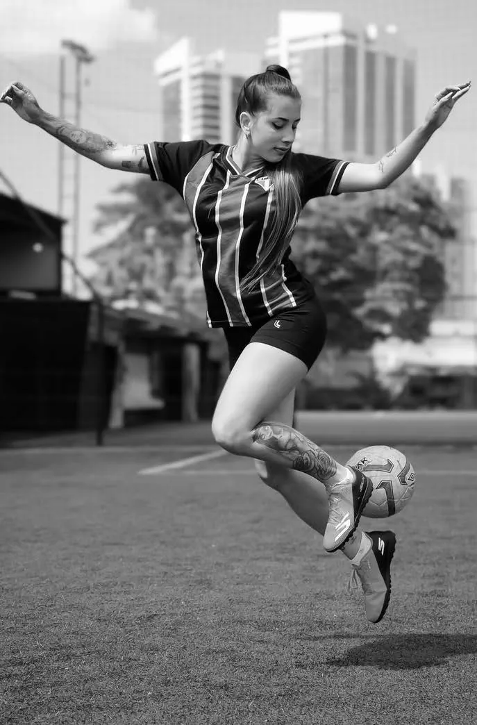 Jogadora chutando uma bola em um campo de grama