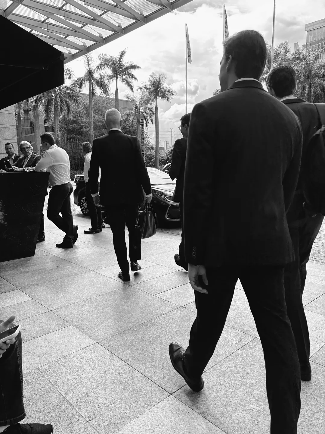 Executivos de terno caminhando em uma calçada, em preto e branco
