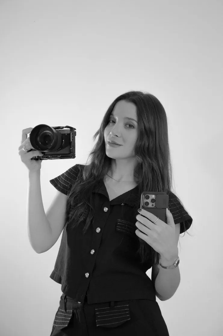 Amanda Tallya segurando uma câmera e um celular